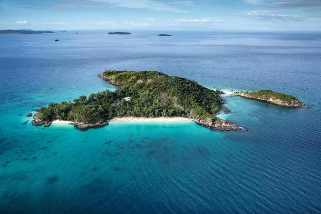Aerial view of Constance Tsarabanjina near Madagascar, showing turquoise water around a lush green, private island surrounded by open sea
