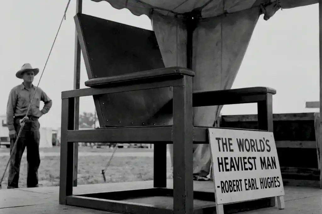 Robert Earl Hughes stands beside a sign reading “The World’s Heaviest Man,” marking his half a ton and 1,041 pounds milestone.