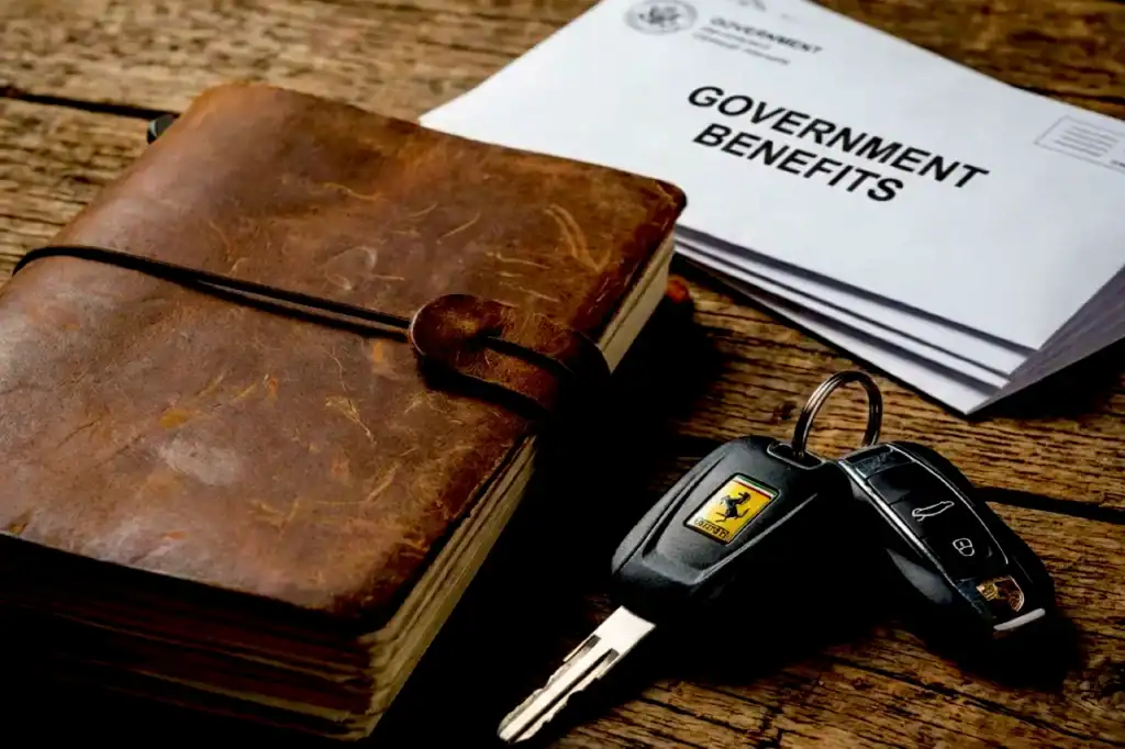 Brown leather wallet and government benefits paperwork sit beside a Ferrari car key fob with the prancing horse emblem, tied to a welfare scam story.