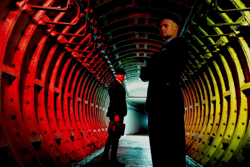 Inside the Scotland nuclear bunker’s Cold War underground tunnel, blast doors in red steel frame a descent into a stark corridor.