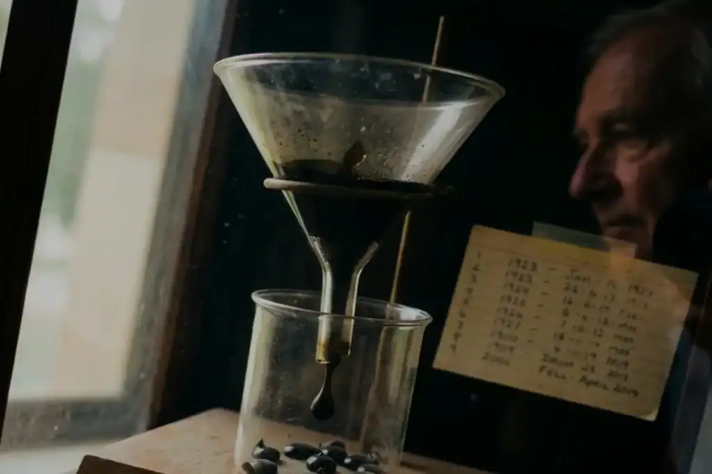 Black pitch clings to a glass funnel above a beaker as drops form in the 97-year Pitch Drop Experiment at the University of Queensland.