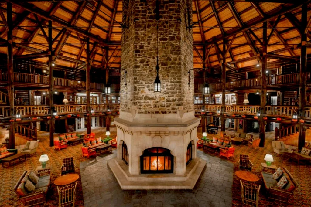 Warm interior view of Fairmont Château Montebello with a towering stone fireplace at the center and surrounding wooden rotunda details.