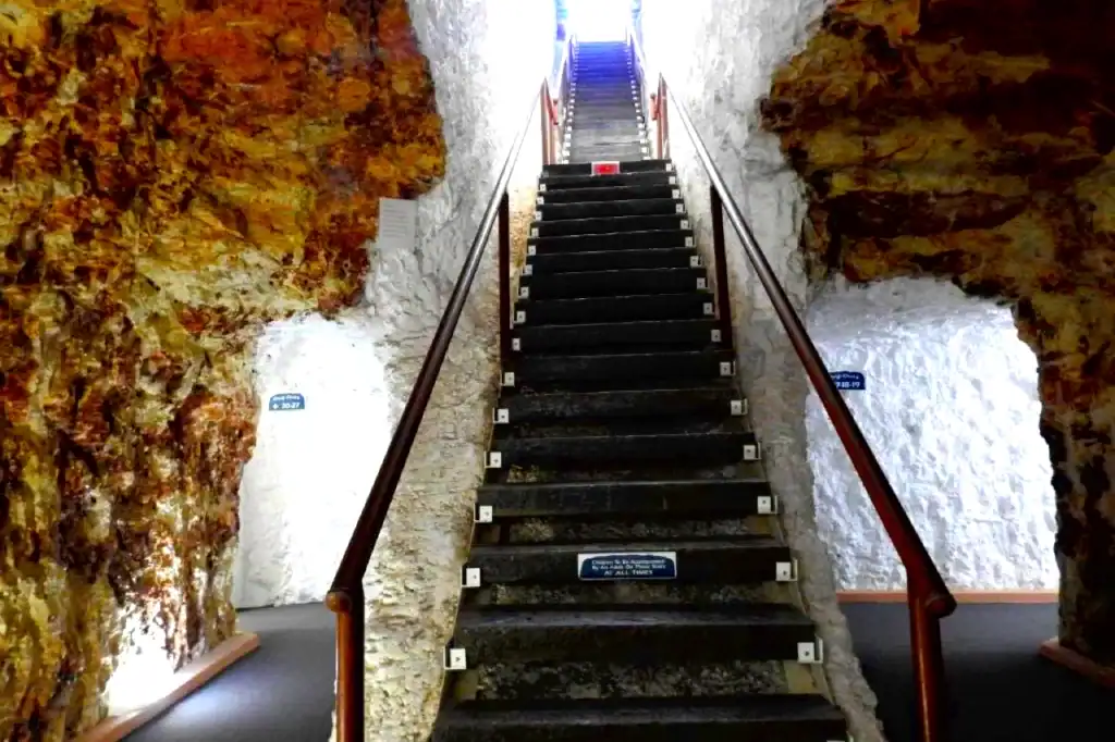 Stairs descend into the White Cliffs Underground Motel within sandstone corridors at White Cliffs in New South Wales, under the Australian outback heat.