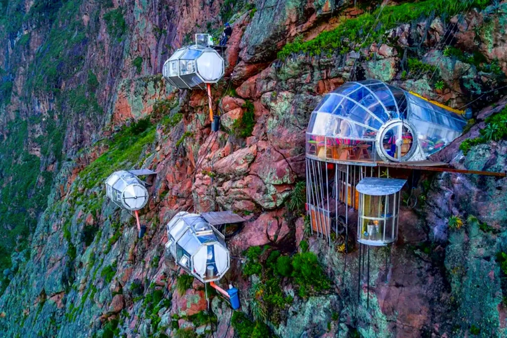 Transparent dome pods hang against a rugged cliff in Peru’s Sacred Valley, part of Skylodge Adventure Suites’ sky-high accommodation experience.