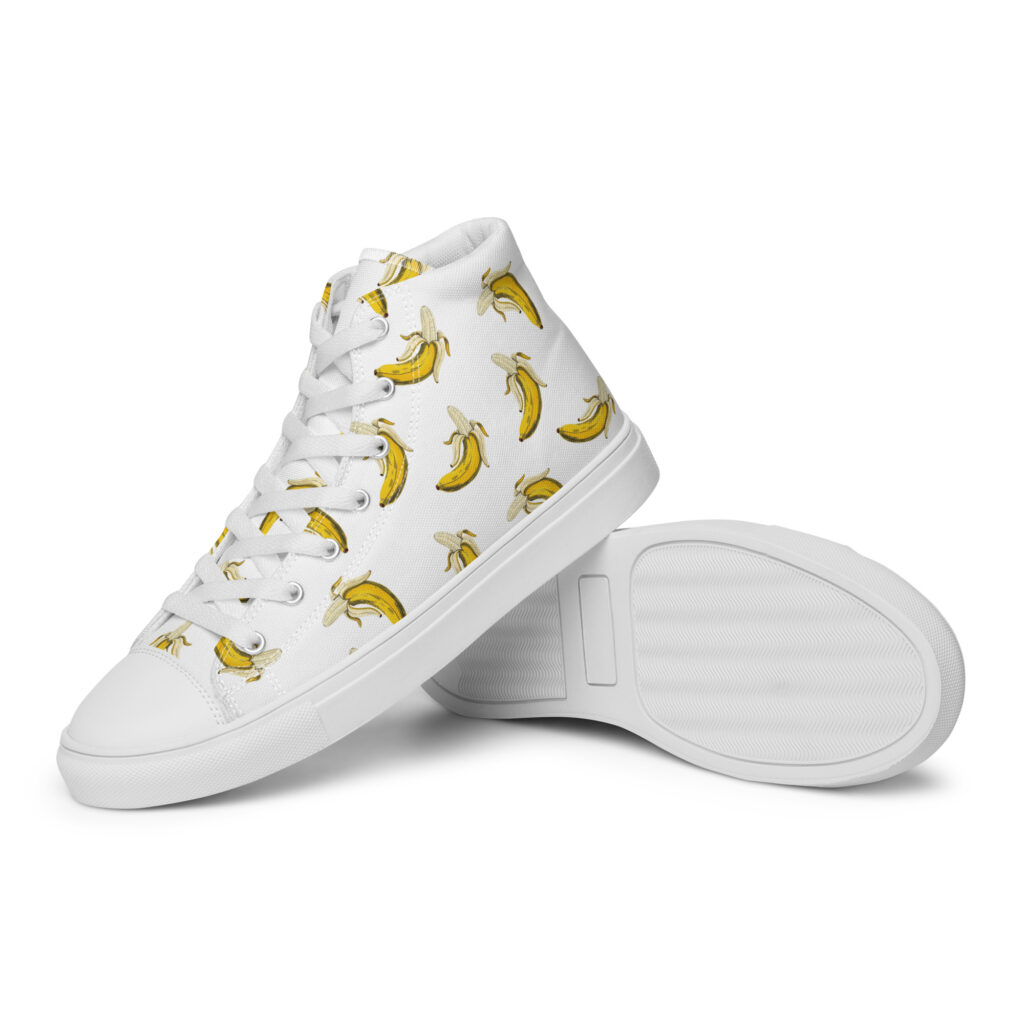 White high-top women’s canvas shoes with a bold banana print, lace-up front, and clean rubber outsole detail with matching tones.